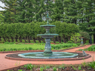 Historic Victorian garden fountain in a courtyard backed by pine trees