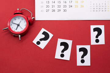 a question mark on a white sheet ,a calendar and a red alarm clock . FAQ frequency asked questions, Answer, Information and Brainstorming Concepts