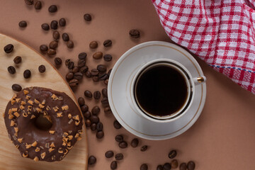 Fresh aromatic coffee in a mug with coffee beans and donut. Morning coffee. Coffee break.