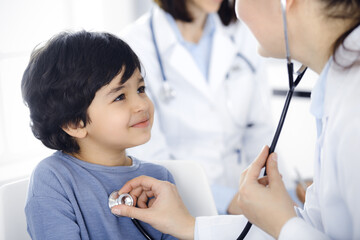 Doctor-woman examining a child patient by stethoscope. Cute arab boy at physician appointment. Medicine concept