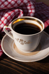 A cup of aromatic black coffee and coffee beans on the table with cinnamon sticks. Morning espresso coffee for breakfast in a beautiful white cup.