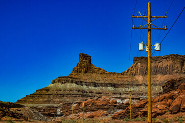 Wooden pole with electric wires on the background of Layered geological formations of red rocks.