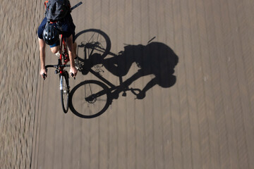 Panning shot from above of a young male riding his racing bike with sahrp shadow on the blurry...