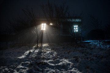 wooden house in winter forest. Mountain house in the snow at night. Misty night.