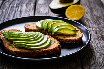 Delicious sandwich - avocado with lemon juice on toasted bread on wooden table