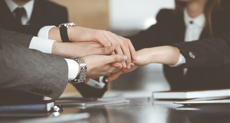 Unknown business people group joining hands in modern office. Businessmen and women making circle with their hands as a team, close-up