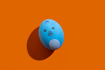 Happy easter. Funny bunny decor. Festive gift. Holiday celebration. Blue egg painted pretty rabbit snout isolated on orange copy space background.
