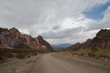 Road trip into the wild. Traveling along the empty dirt road across the arid desert and rocky mountains. 