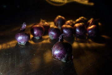 Vegetable concept. Onions in dark on wooden table. Selective focus
