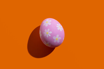 Easter symbol. Festive gift card. Spring holiday decoration. Abstract background. Pink egg with white floral ornament pattern isolated on orange copy space.