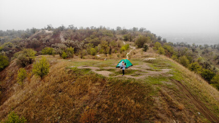 Obraz premium Aerial top view of happy mother and daughter near tent at hill. Active time together