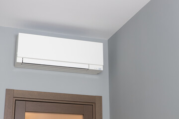 White air conditioning on gray wall inside room in apartment over door, switched off. Interior in calm neutral tones. Concept interior details, comfort devices, home climate stations. Copy space