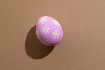 Pretty easter egg. Festive gift card. Spring holiday decoration. Abstract background. Pink paschal symbol with white floral ornament pattern isolated on beige copy space.