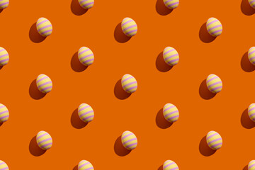 Easter seamless pattern. Festive banner. Gift card. Holiday decoration. Abstract background. Colorful eggs of yellow and pink striped ornament isolated on orange.