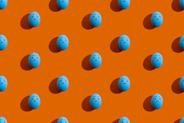 Easter pattern. Seamless banner. Conceptual art. Holiday troubles. Abstract background. Blue eggs with sad face painted ornament isolated on orange.