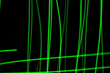 Green thin lines of light on black background. Laser irregular light beams. Luminous, bright threads of green color with high density.