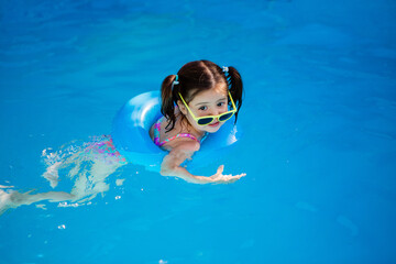 little girl with glasses in the swimming pool in the swimming circle, children's summer vacation on the weekend
