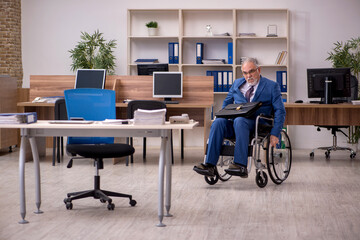 Old businessman employee in wheel-chair working in the office