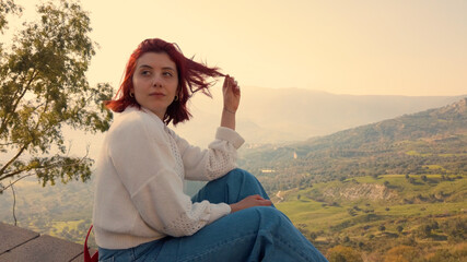Giovane ragazza con maglia bianca si affaccia da una montagna 