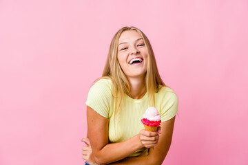 Young russian woman eating an ice cream isolated laughing and having fun.