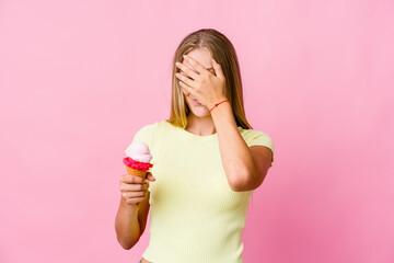 Young russian woman eating an ice cream isolated covers eyes with hands, smiles broadly waiting for a surprise.