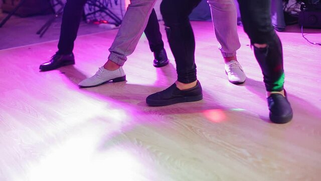 Guys dance on the dance floor in a club. Close-up foot shots