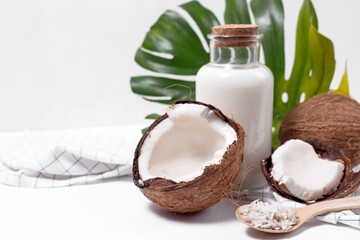 Coconut milk in a glass bottle. Whole and cracked coconut on white background