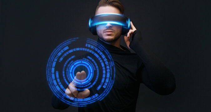 Man on dark virtual reality background. Guy using VR helmet. Augmented reality, future technology, game concept. Blue neon light. Futuristic holographic interface to display data.