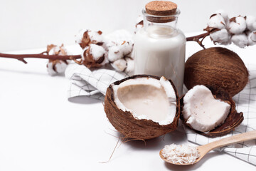 Coconut milk in a glass bottle. Whole and cracked coconut on white background
