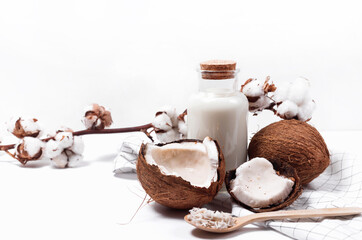 Coconut milk in a glass bottle. Whole and cracked coconut on white background