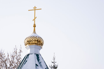 The golden dome and cross of the chapel against the sky on a winter day.