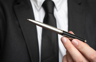 Businessman giving pen for your signature on clipboard