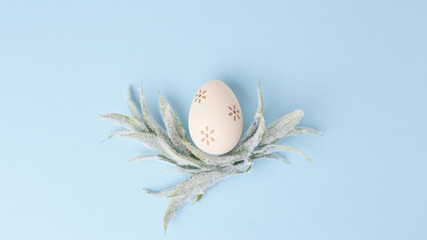 holiday concept. simple composition of a decorative Easter egg and fluffy twigs on a blue background. flat lay, copy space