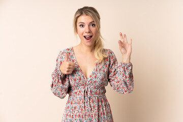 Blonde woman over isolated background showing ok sign and thumb up gesture