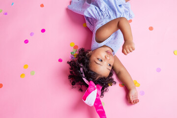 two charming little girls with dark skin and curly hair in beautiful dresses are lying on the floor in confetti