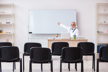 Old male doctor lecturer in the classroom during pandemic