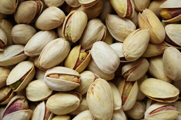 Tasty pistachios as background texture, flat lay. Pile of pistachios in the peel close up. Pistachios healthy omega-3 fatty acid. Healthy food and snacks vegan food. 