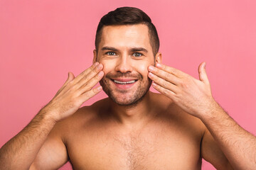Obraz premium Photo of smiling young beautiful man standing isolated over pink wall background naked. Man's skincare concept in a bathroom.