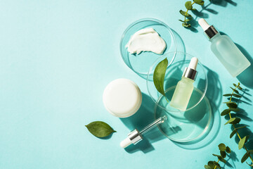 Cosmetic laboratory concept . Glass petri dish with cosmetic products and serum bottles at blue background. Flat lay image with copy space. - obrazy, fototapety, plakaty