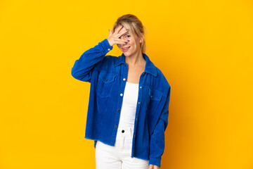 Young Russian woman isolated on yellow background covering eyes by hands and smiling