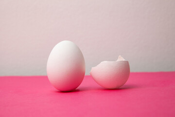 White eggs near broken shell on pink table
