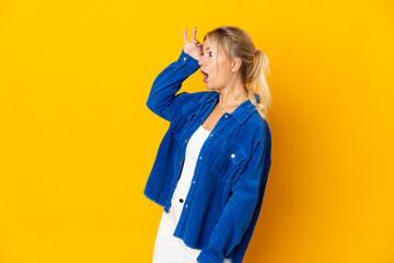 Young Russian woman isolated on yellow background with surprise expression while looking side