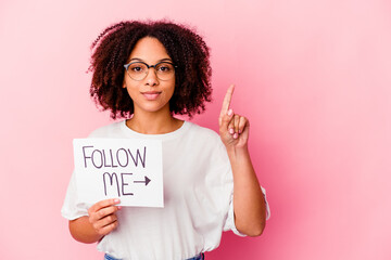 Young african american mixed race woman holding a follow me concept showing number one with finger.