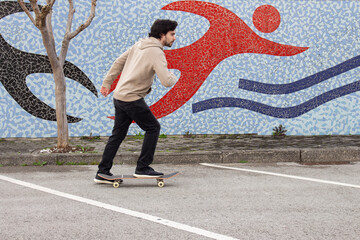 Young skater man skateboarding in the parking lot. Wearing casual street clothes. Doing sports in the street.