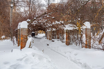 Snowbound garden house with wild grapes in a city park