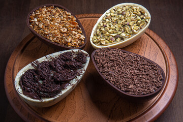 Pistachio, chocolate, hazelnut and white chocolate stuffed easter eggs on a wooden stand.