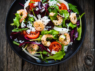 Prawn salad with white rice, lettuce, cherry tomatoes and onion on wooden background
