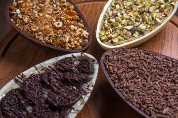 Pistachio, chocolate, hazelnut and white chocolate stuffed easter eggs on a wooden stand.