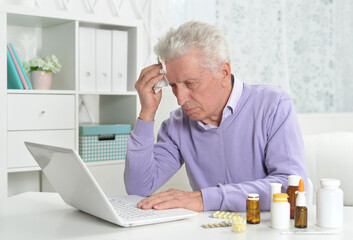 Portrait of sad sick senior man using laptop