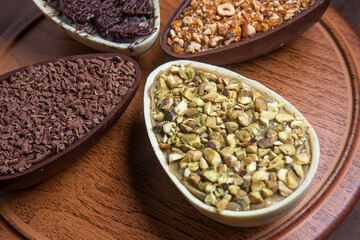 Pistachio, chocolate, hazelnut and white chocolate stuffed easter eggs on a wooden stand.